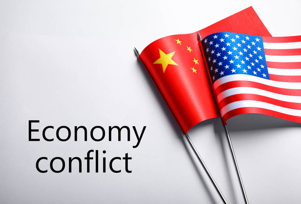 USA and China flags near words ECONOMY CONFLICT on white background, flat lay - Foto, Bild