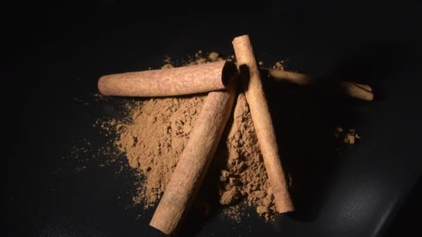 Powder cinnamon and sticks rotating in black background, food spice - Footage, Video