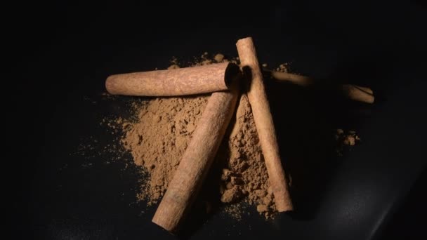Sticks and powder cinnamon rotating in black background, food spice - Footage, Video