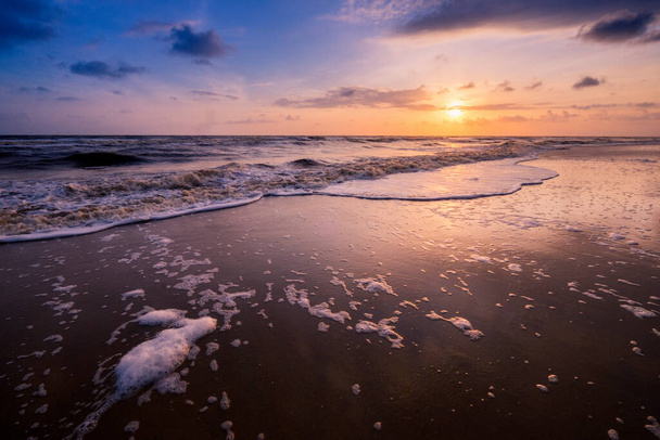 Красивий хмарний пейзаж над морем з м'якою хвилею блакитного океану на піщаному пляжі під час сходу сонця
. - Фото, зображення