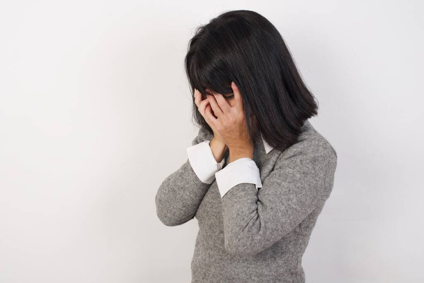 Θλιβερή νεαρή λευκή γυναίκα κλαίει και καλύπτει το πρόσωπό της με τα χέρια.  - Φωτογραφία, εικόνα