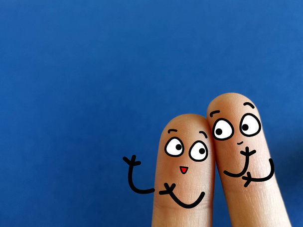 Dos dedos están decorados como dos personas. Están hablando el uno al otro felizmente. - Foto, imagen