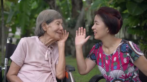 Hija hablando con la mujer anciana con discapacidad auditiva  - Imágenes, Vídeo