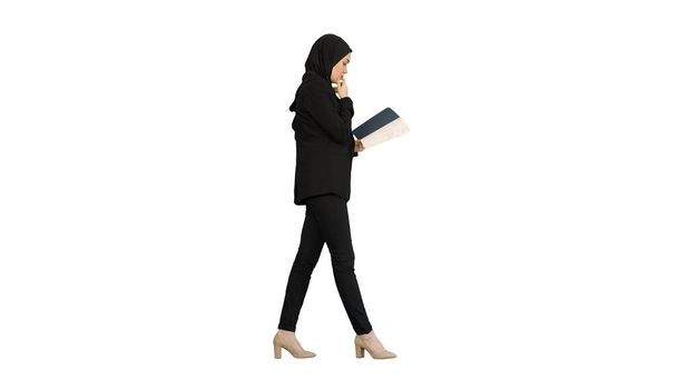 Muslim Businesswoman reading her business planner while walking - Photo, image