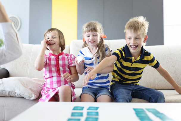 Boy and two girls laugh and play board game - Фото, зображення