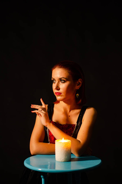 Misteriosa magia de cerca, mujer conjurando sobre la vela encendida en aislamiento sobre fondo negro. El concepto de predicción, clarividencia y adivinación. - Foto, imagen