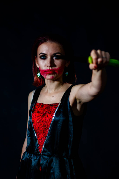 Frau mit gruseliger Schminke hält Messer auf dunklem Hintergrund, Halloween-Konzept  - Foto, Bild