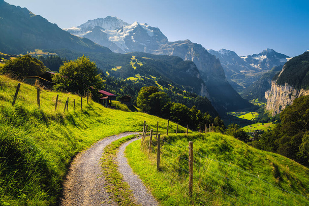 Paisagem alpina de tirar o fôlego com prados verdes e montanhas nevadas. Aldeia de Wengen e vale Lauterbrunnen com falésias altas, Bernese Oberland, Suíça, Europa - Foto, Imagem