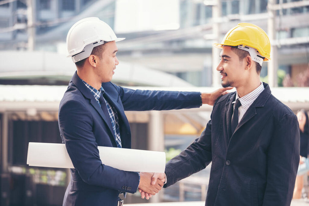 Civil Construction engineer teams shaking hands together wear work helmets worker on construction site. Foreman industry project working engineer teamwork. Two asian engineer team shake hands together - Foto, immagini