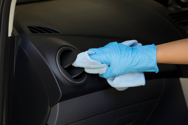 Hand wearing rubber gloves, using a microfiber cloth to clean and remove dust from the car air vent grille. Cleaning air vent grille. - Photo, Image