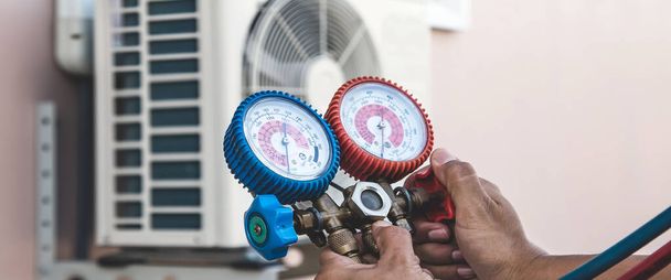 Air repair mechanic using measuring pressure gauge equipment for filling home air conditioner after cleaners and checking maintenance outdoor air compressor unit. - Photo, Image