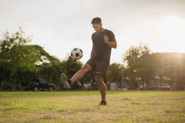 Man playing football at green field. asian soccer player playing football. - Foto, afbeelding