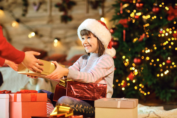 Cheerful girl receiving Christmas gift from parent - Valokuva, kuva