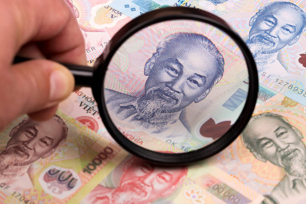 Vietnamees geld in een vergrootglas een zakelijke achtergrond - Foto, afbeelding
