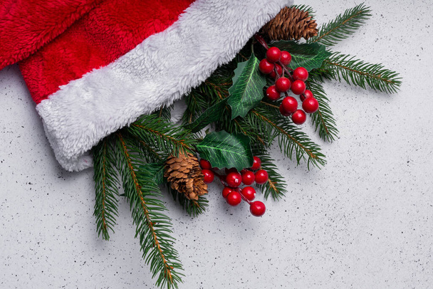 focalisation sélective. Aménagement de la lumière de Noël, branches d'arbre et décorations dans un chapeau de Noël doux rouge - Photo, image
