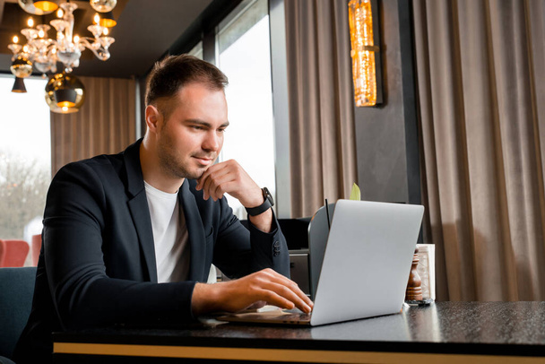 Mladý podnikatel pracující na notebooku v moderní kavárně v hotelu - Fotografie, Obrázek