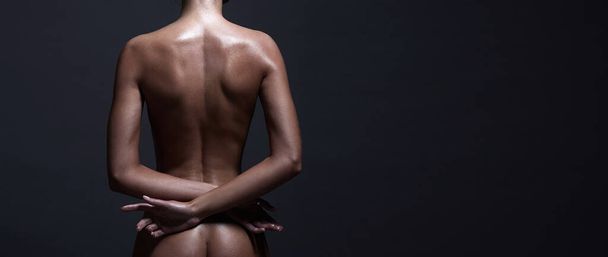 Beautiful nude girl in studio. Naked woman back in dark studio - 写真・画像