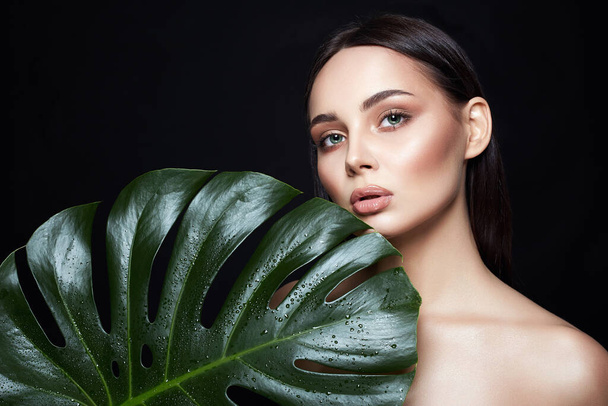 Beauty Portrait of brunette girl in palm leaves. Beautiful young woman with Make-up. Natural cosmetics concept - Foto, Imagem
