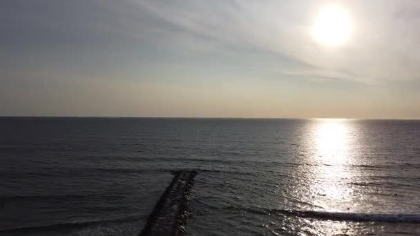 Luchtopname in beweging van zonsondergang in de Atlantische Oceaan in Costa da Caparica, Lissabon, Portugal. Luchtfoto van het strand en zonsondergang tijdens de zonsondergang. - Video