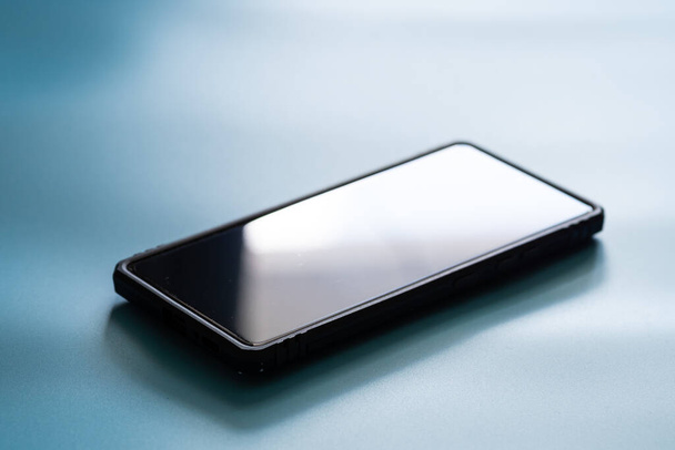 Μαύρη οθόνη smartphone με τη θήκη και να αντιγράψετε χώρο σε μπλε φόντο χρώμα διάθεση και ύφος - Φωτογραφία, εικόνα