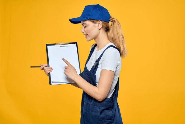 mujer en el trabajo documentos uniformes servicio de mensajería fondo amarillo - Foto, imagen