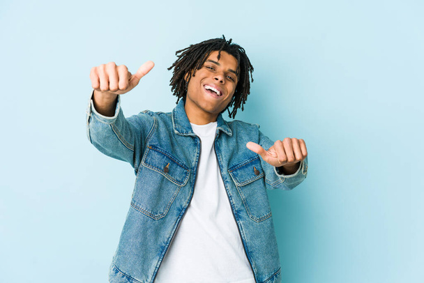 Jeune homme noir vêtu d'un jean levant les pouces vers le haut, souriant et confiant. - Photo, image