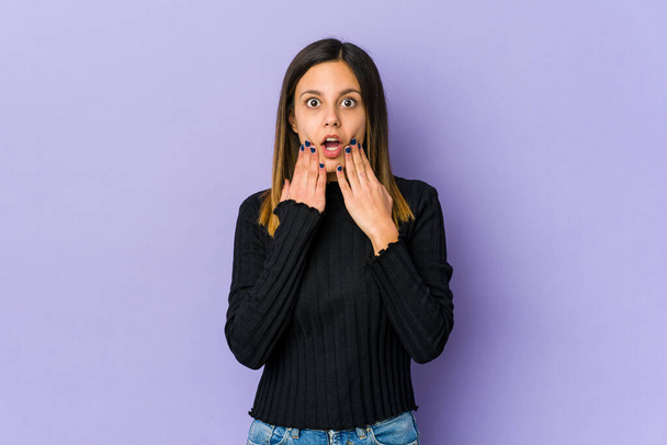 Young woman isolated on purple background shocked, covering mouth with hands, anxious to discover something new. - Photo, Image