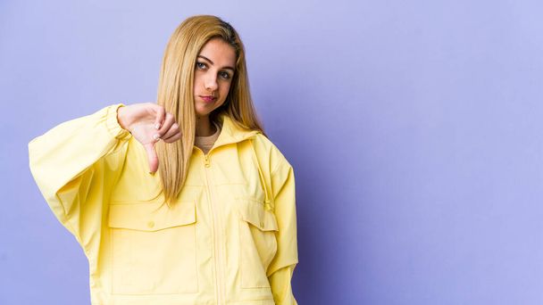 Young blonde woman isolated on purple background showing a dislike gesture, thumbs down. Disagreement concept. - Photo, Image