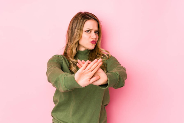 Young caucasian woman isolated on pink background standing with outstretched hand showing stop sign, preventing you. - Photo, Image
