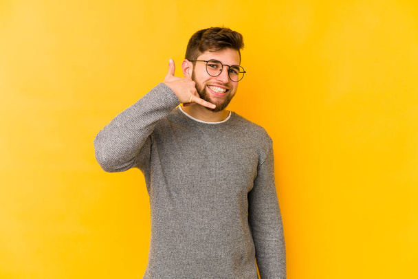 Young caucasian man isolated on yellow background showing a mobile phone call gesture with fingers. - Photo, Image