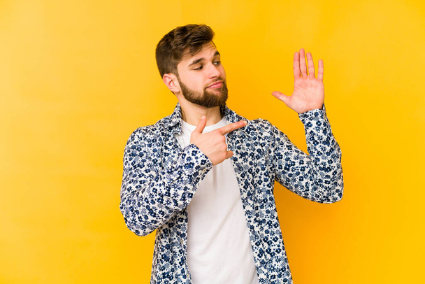 Fiatal kaukázusi férfi elszigetelt sárga háttér mosolygós vidám bemutató szám öt ujjakkal. - Fotó, kép