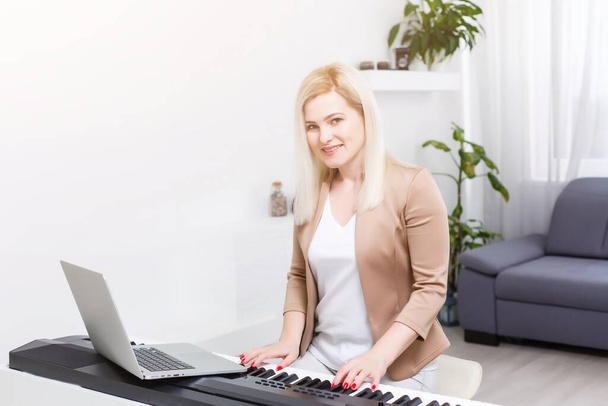 Evde online ders sırasında klasik dijital piyano çalan kadın müzisyen, karantina sırasında sosyal mesafe, kendini tecrit, online eğitim konsepti - Fotoğraf, Görsel