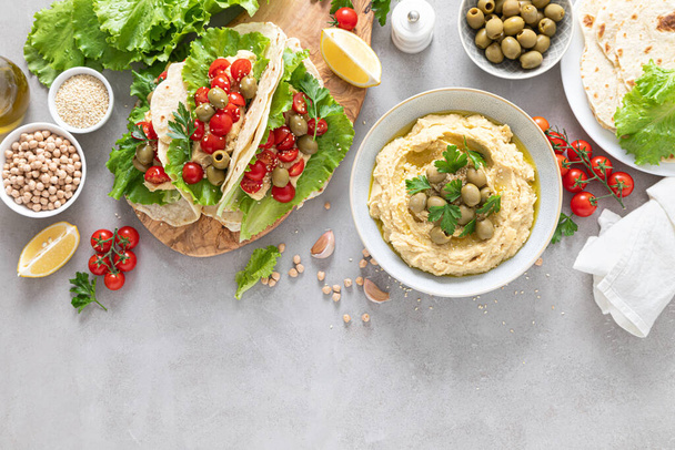 Tortilla wraps with chickpea hummus, fresh tomatoes and olives, vegan food - Fotografie, Obrázek