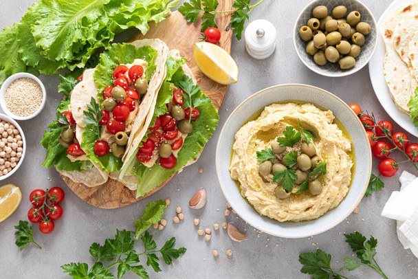 Tortilla wraps with chickpea hummus, fresh tomatoes and olives, vegan food - 写真・画像