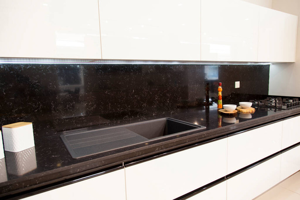 Interieur der luxuriösen modernen Küche, weiße Schränke schwarzer Granit und Acryl-Spüle - Foto, Bild