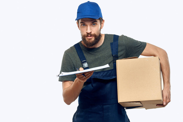 Corriere maschio di lavoro con scatola in mano documenti consegna servizio sfondo leggero - Foto, immagini