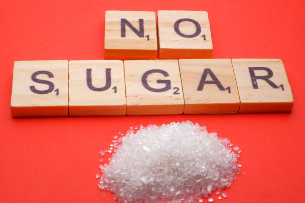 Concepto de salud. Azúcar con una redacción NO AZÚCAR sobre fondo rojo - Foto, imagen