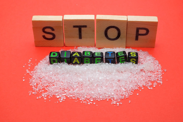Концепция здоровья. Sugar with a STOP DIABETES wording, glucometer and insulin on red background - Фото, изображение