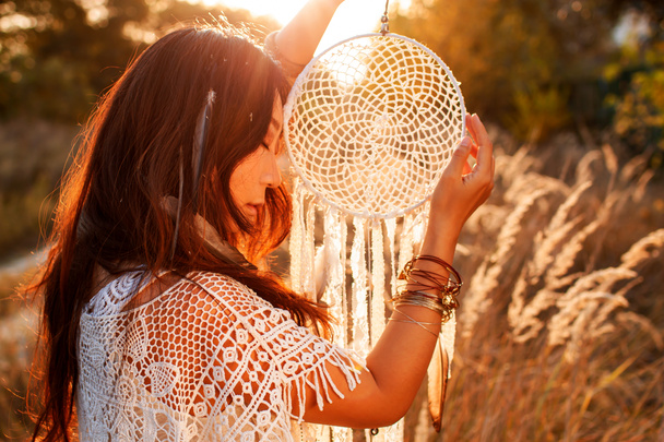 Portrait of a beautiful boho woman in a sunny field at sunset. - Foto, Imagem