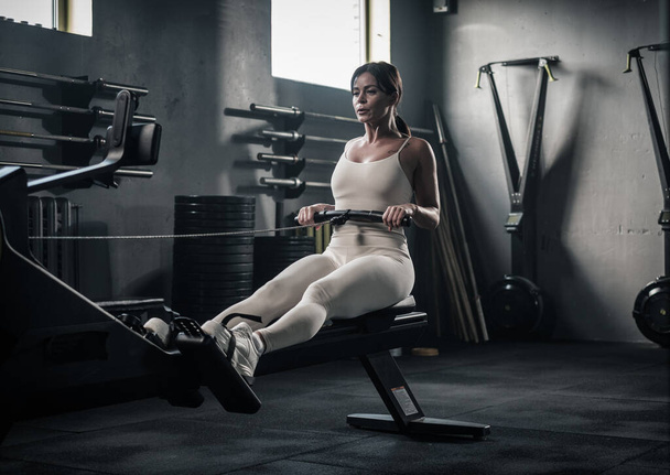 Mujer atlética tiene entrenamiento en la máquina de remo . - Foto, Imagen
