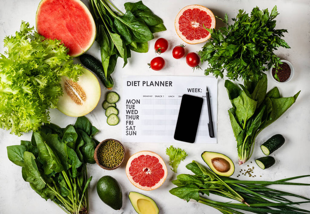 Smartphone und Ernährungsplan mit Lebensmitteln. Ansicht von oben - Foto, Bild