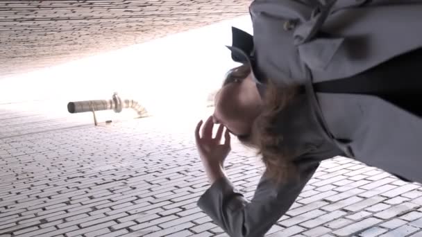 asiático modelo bonito vestindo casaco de trincheira em pé perto de paredes tiro de ponto inferior - Filmagem, Vídeo