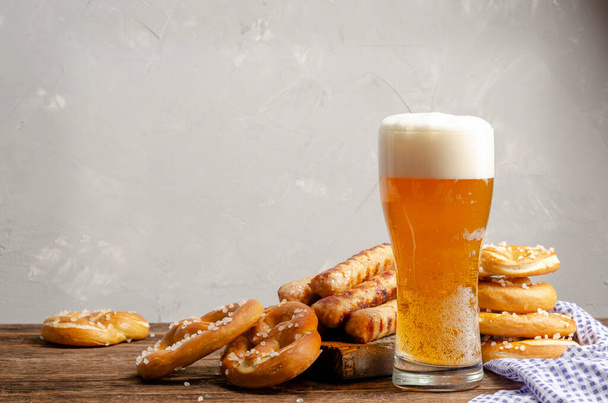 Cibo Oktoberfest, pretzel bavaresi con bicchiere di birra su vecchio sfondo di legno rustico - Foto, immagini