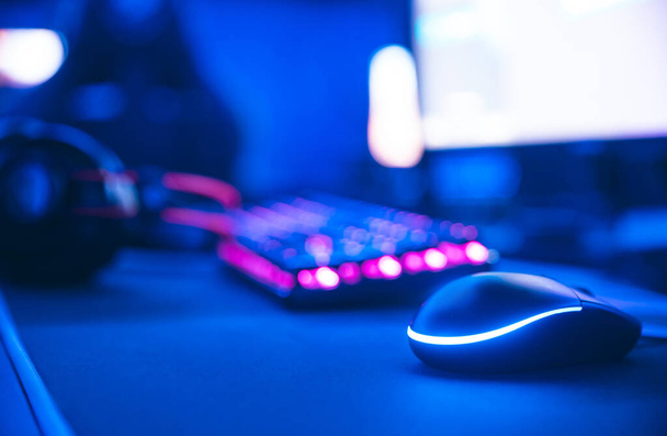 Рабочее место для новой игровой мыши и клавиатуры с размытым розовым неоновым светлым фоном - Фото, изображение