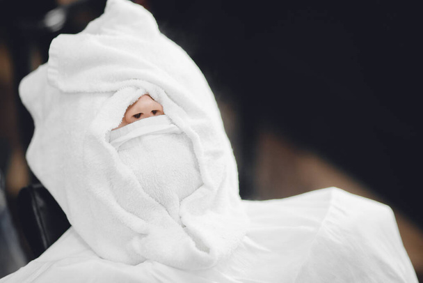 Az ember a fodrászszékben ül és forró törülközővel gőzöli az arcát a királyi szakáll borotvája előtt. - Fotó, kép