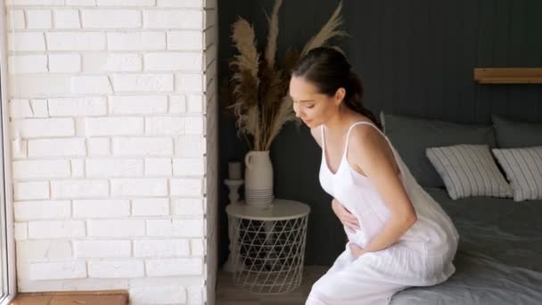 Jonge zwangere vrouw beroertes buik opstaan uit bed - Video