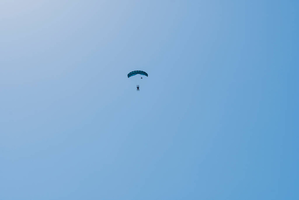 Tandem parachute jump. Silhouette of skydiver flying in blue clear sky. Concepts of extreme sport and adrenaline. - Photo, Image