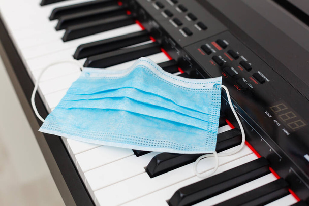 Защитная медицинская маска гриппа на фортепианной клавиатуре крупным планом - Фото, изображение
