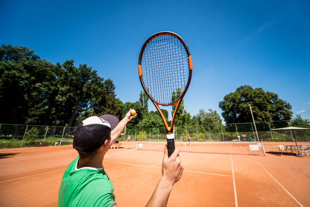 Young athletic man playing tennis on the court. - Фото, изображение