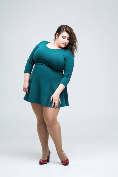 Sexy plus size fashion model in green dress, fat woman on gray background, body positive concept, full length portrait - Fotó, kép